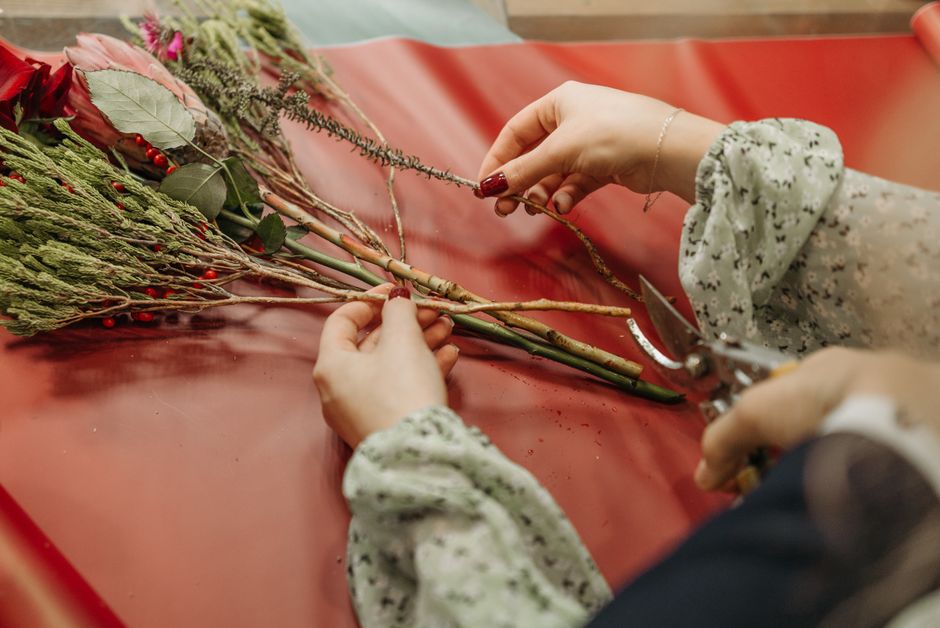 Close-up of hands arranging a flower bouquet in a shop, emphasizing creativity and craft.